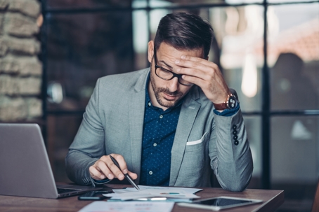 a man looking at documents by his laptop