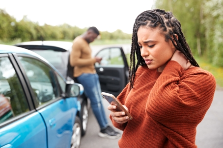 A man and a woman outside of their cars after an accident.